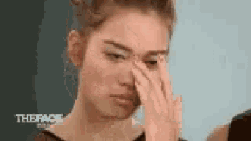 a woman is covering her nose with her hand while crying .