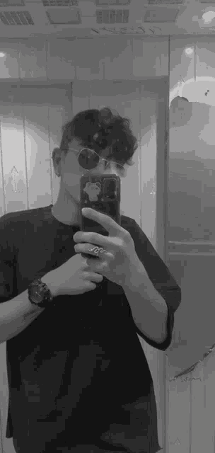 a man is taking a picture of himself in a mirror with his cell phone .