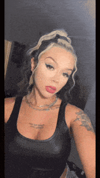 a woman in a black tank top has a tattoo on her chest that says ' i love you '