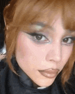 a close up of a woman 's face with makeup on and a black jacket .