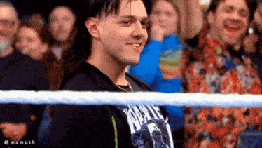 a man wearing a black shirt that says wwe stands in a crowd