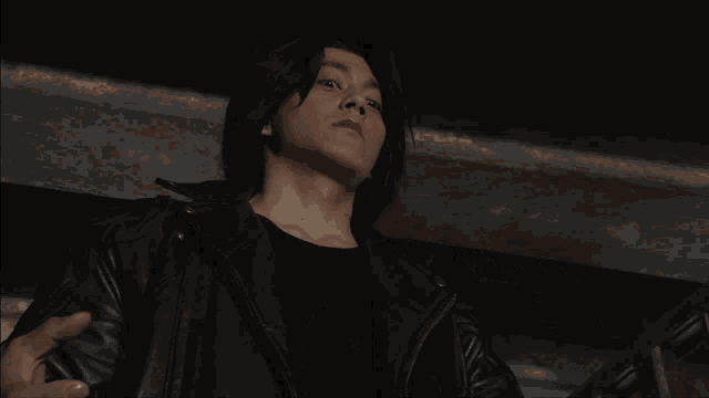 a man in a black leather jacket has a tattoo on his arm