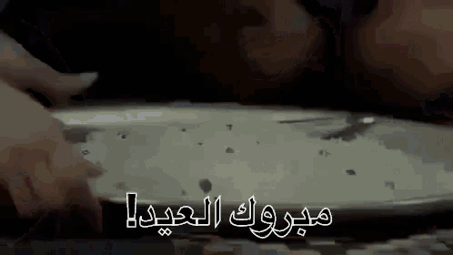a close up of a person 's hand holding a piece of metal with arabic writing on it .