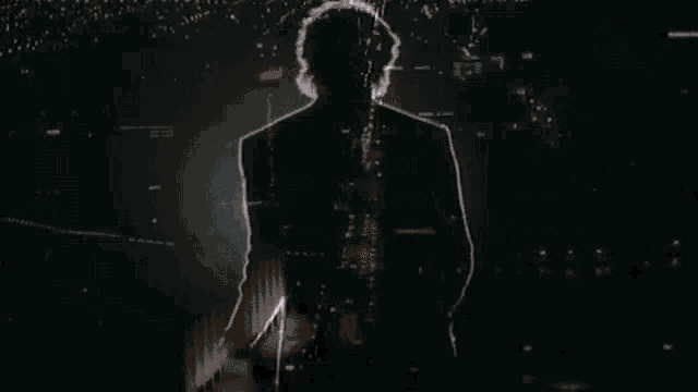 a silhouette of a person standing in front of a light in the dark .