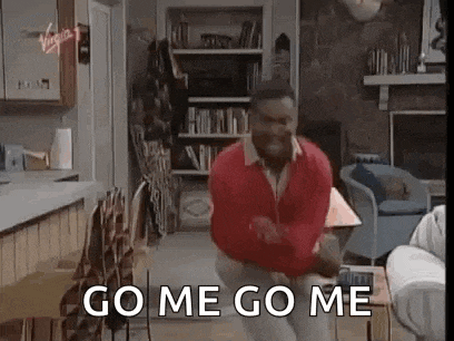 a man in a red sweater is dancing in a living room while saying `` go me go me '' .