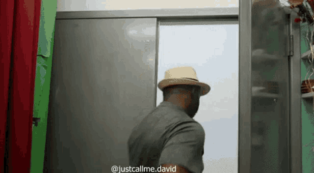 a man in a hat is standing in front of a door .