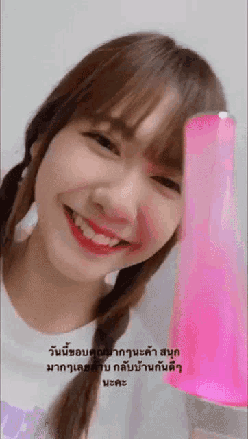 a girl is smiling and holding a pink object in front of her