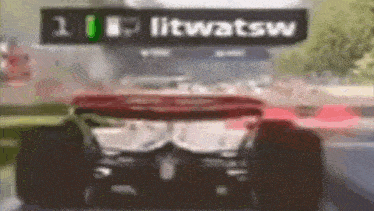 a blurry picture of a race car with a sign that says litwatsw in the background