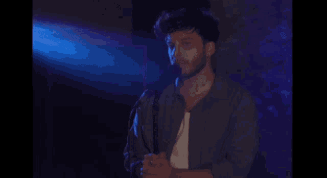 a man with a beard is standing in front of a microphone .