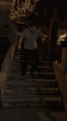 a man in a grey shirt is walking down a set of stairs