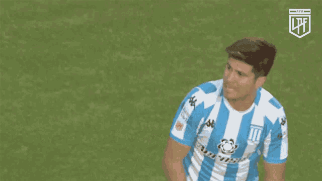 a man in a blue and white striped shirt is giving a thumbs up sign