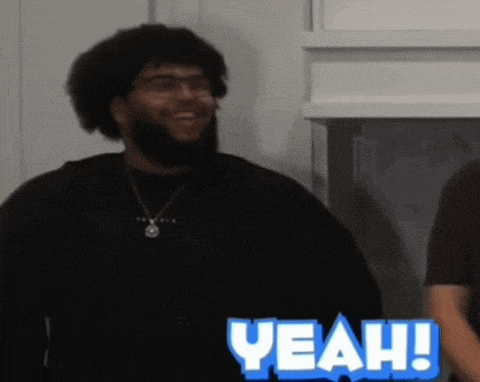 a man with a beard is smiling in front of a sign that reads yeah