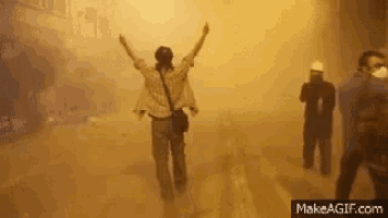 a woman is walking down a street with her arms outstretched in a dust storm .