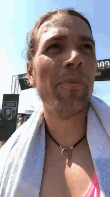 a woman with a towel around her neck looks up at the sky