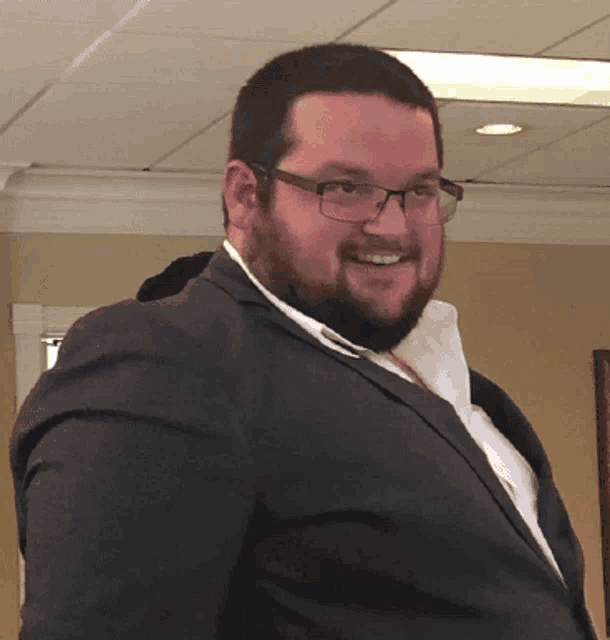 a man with glasses and a beard is smiling for the camera