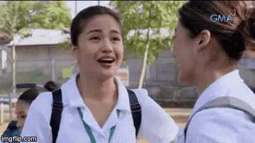 two young women are talking to each other in a park .