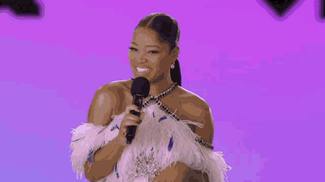 a woman singing into a microphone with a purple background
