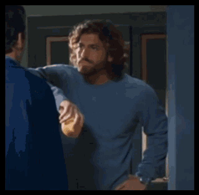 a man in a blue sweater is standing next to another man in a blue sweater