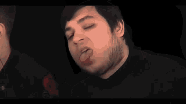 a man with a beard is sticking his tongue out and making a funny face .