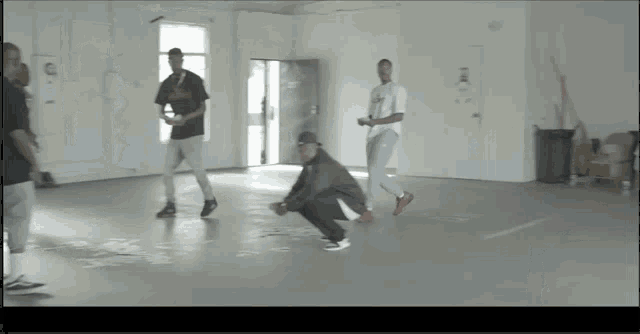 a group of men are squatting on the floor in a room with a sign on the wall that says ' a ' on it