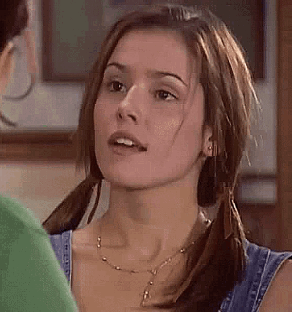 a woman with pigtails and a necklace is talking to another woman in a room .