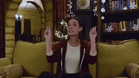 a woman sitting on a couch with her hands in the air and a clock in the background