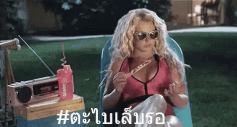 a woman wearing sunglasses is sitting in a chair eating a piece of food .