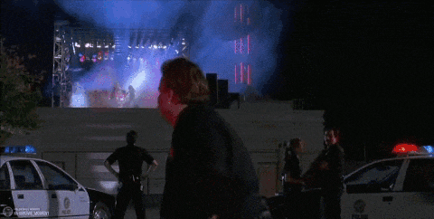 a man in a police uniform is standing in front of a stage with a purple light behind him .