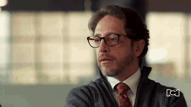 a man wearing glasses and a tie with the letters nc on the bottom