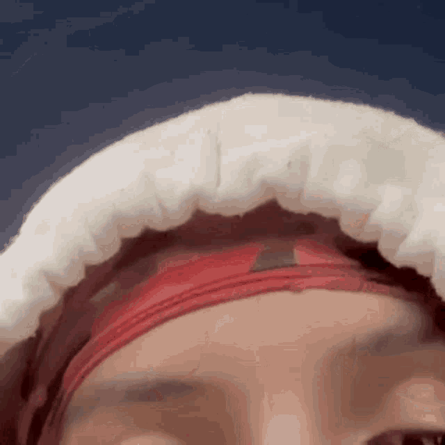 a close up of a person 's face with a red headband and a white blanket on their head .
