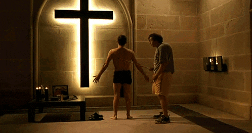two men are standing in front of a cross that is lit up