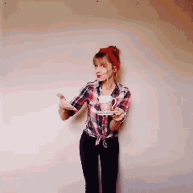 a woman in a plaid shirt is holding a cup