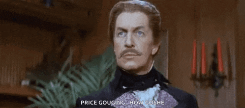 a man with a mustache and a tuxedo is standing in a room .