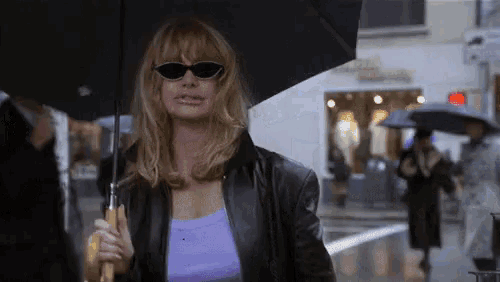 a woman wearing sunglasses is holding an umbrella