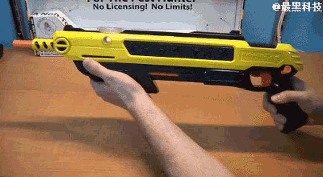 a person is holding a yellow toy gun that says ' no licensing no limits ' on it