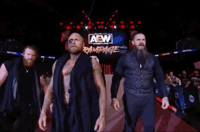 a group of men are walking in front of an aew rampage sign