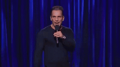 a man is standing on a stage holding a microphone and making a funny face .