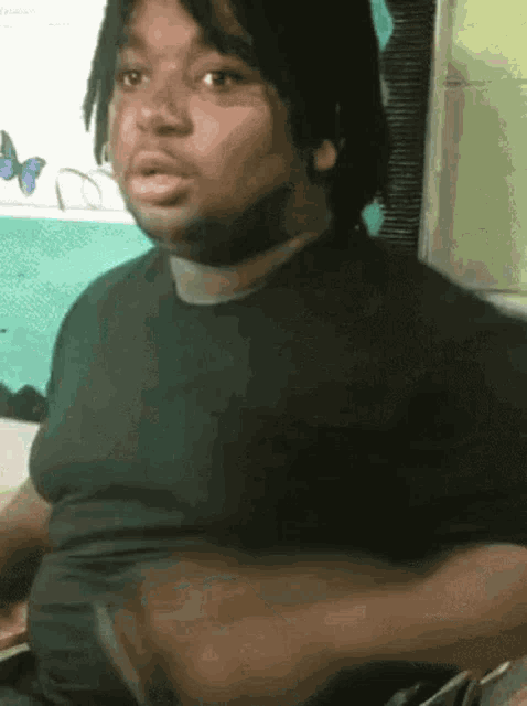 a man with dreadlocks and a black shirt is looking at the camera