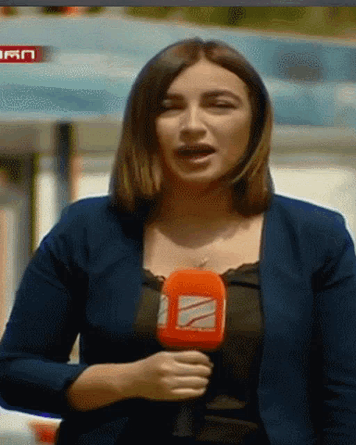 a woman in a blue jacket is holding a microphone with the letter z on it