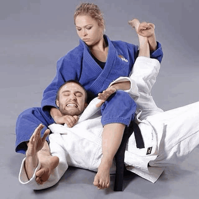 a woman is wrestling a man in a blue kimono .