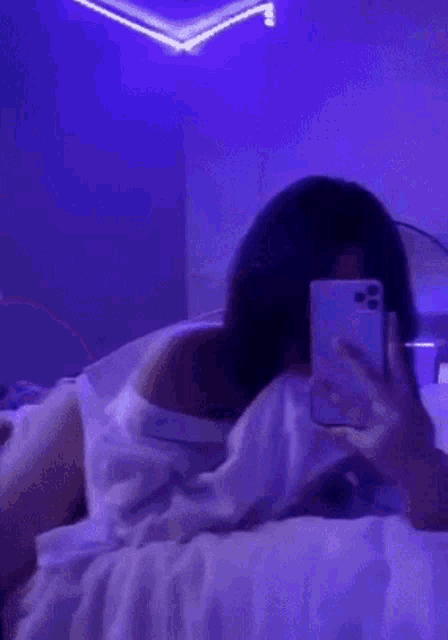 a woman is laying on a bed with a purple light on the wall .