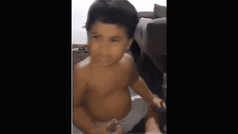 a baby in a diaper is sitting on a couch and looking at the camera .