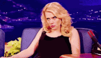 a woman in a black dress is sitting in a chair and making a face