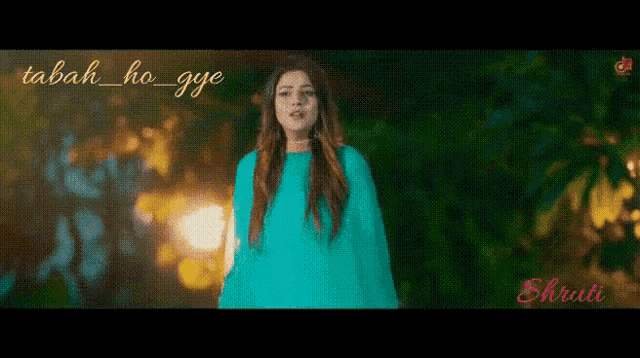 a woman in a blue dress is standing in front of trees at night