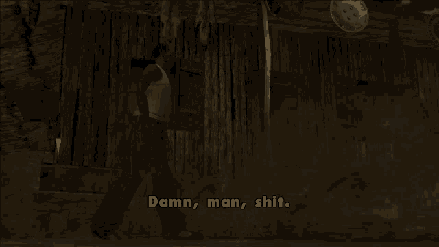 a man in a white tank top walks in front of a wooden building and says damn man shit