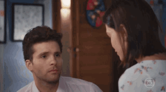 a man and a woman are looking at each other with a camera in the background