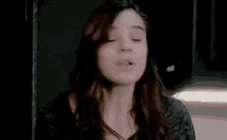 a woman with long hair is making a funny face while standing in a dark room .