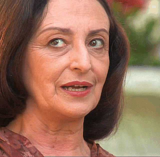 a close up of a woman 's face with a floral shirt on