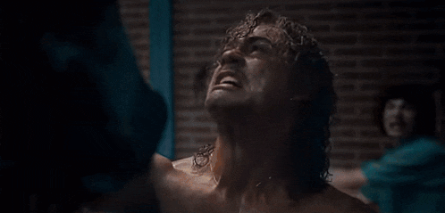 a man is screaming in front of a brick wall in a room .