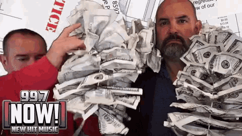 two men are holding a pile of money in front of a 997 now sign